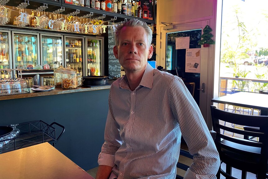A man stands in a bar posing for a photo.