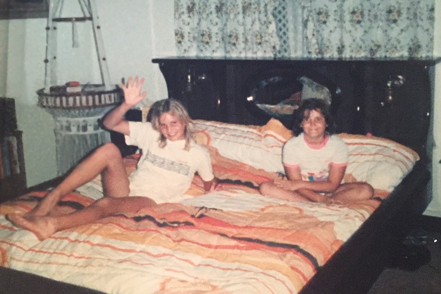 Two girls sit on a waterbed.