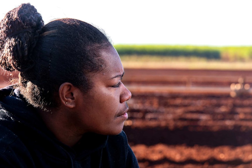 A woman looks out over farming land.