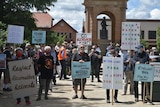 A group of protestors with signs including "go elsewhere karts", "shame council shame", "our rates not for your mates"