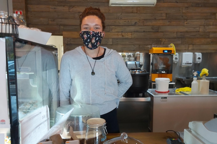 woman wearing mask standing behind the counter in a cafe