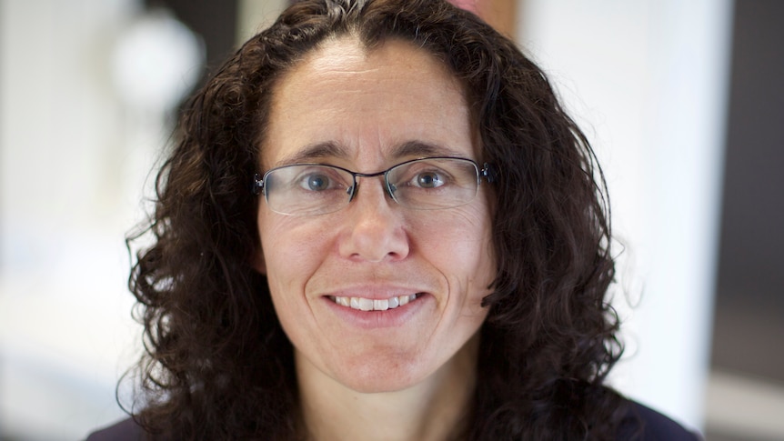 Closely cropped image of a woman with shoulder-length dark hair and glasses smiling.