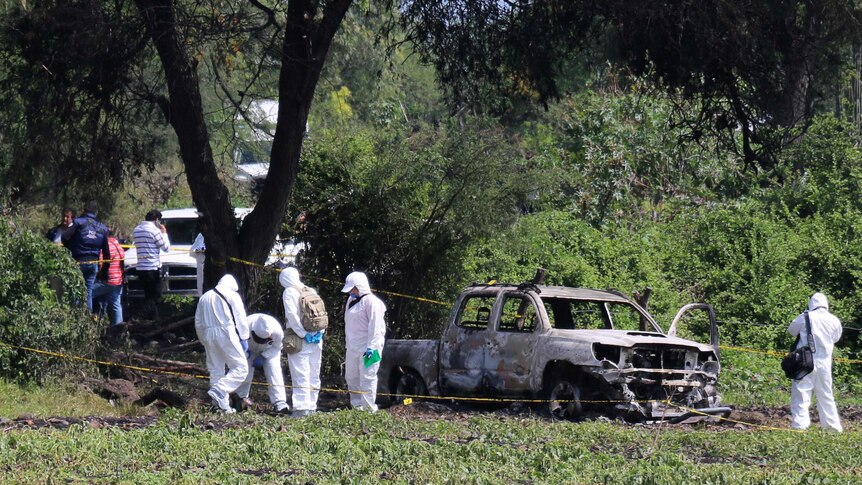 Forensic technicians work at a crime scene where ten people were found dead.