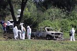 Forensic technicians work at a crime scene where ten people were found dead.