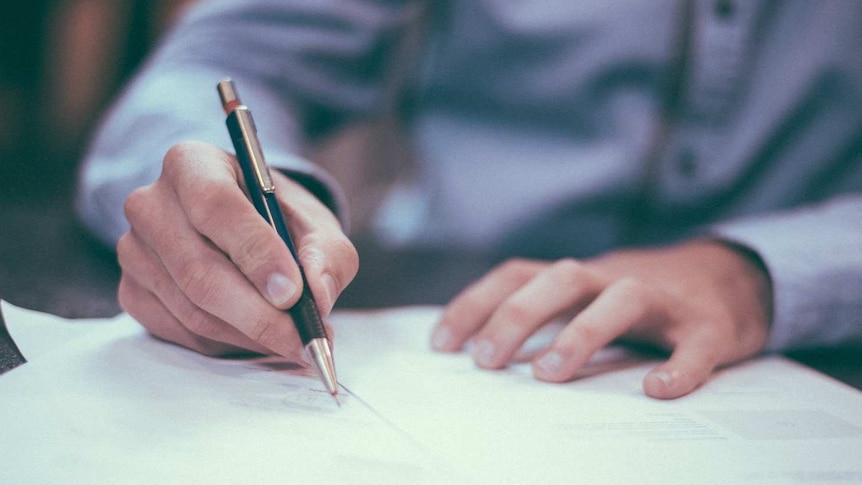 A generic image of a man writing at a table