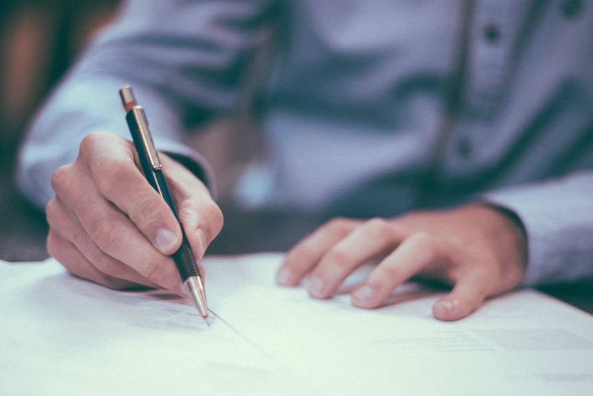 A generic image of a man writing at a table