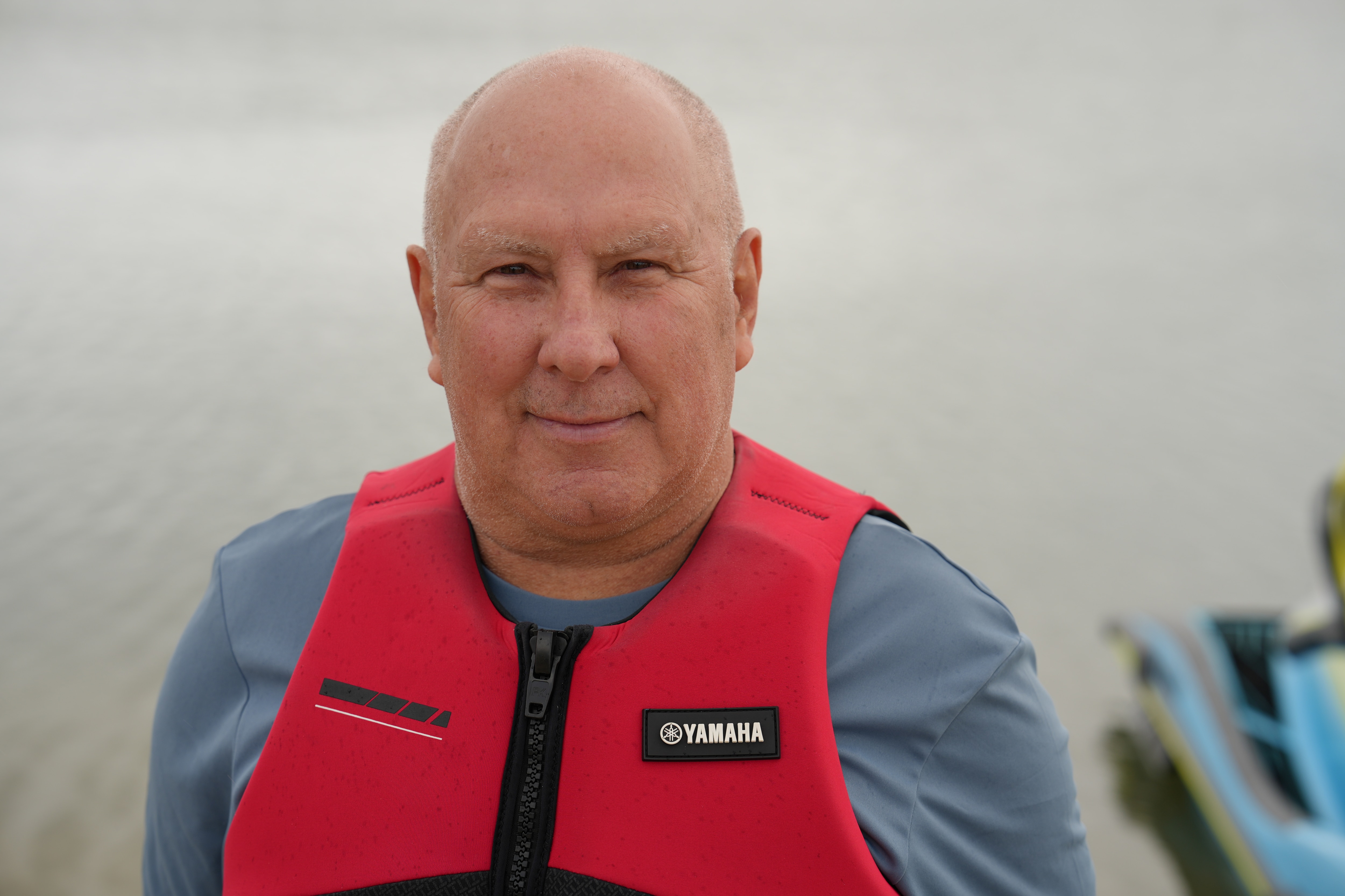 a man in his lifejacket standing in front of a jet ski