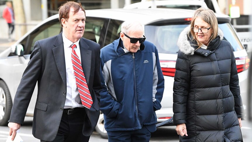 Former school principal and Marist Brother Gerard McNamara (centre) walks into court with a man and woman.