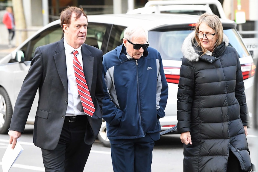 Former school principal and Marist Brother Gerard McNamara (centre) walks into court with a man and woman.