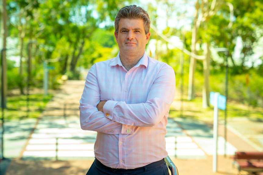 Man in a pink shirt with his arms crossed