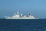 A ship is seen to the centre-left of image on the sea, with several domes on it and what appears to be a Chinese flag.