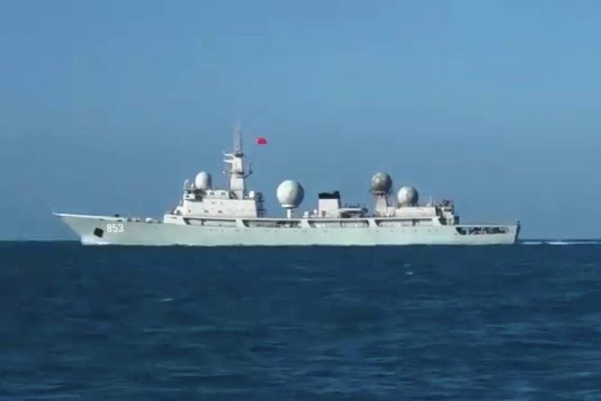 A ship is seen to the centre-left of image on the sea, with several domes on it and what appears to be a Chinese flag.