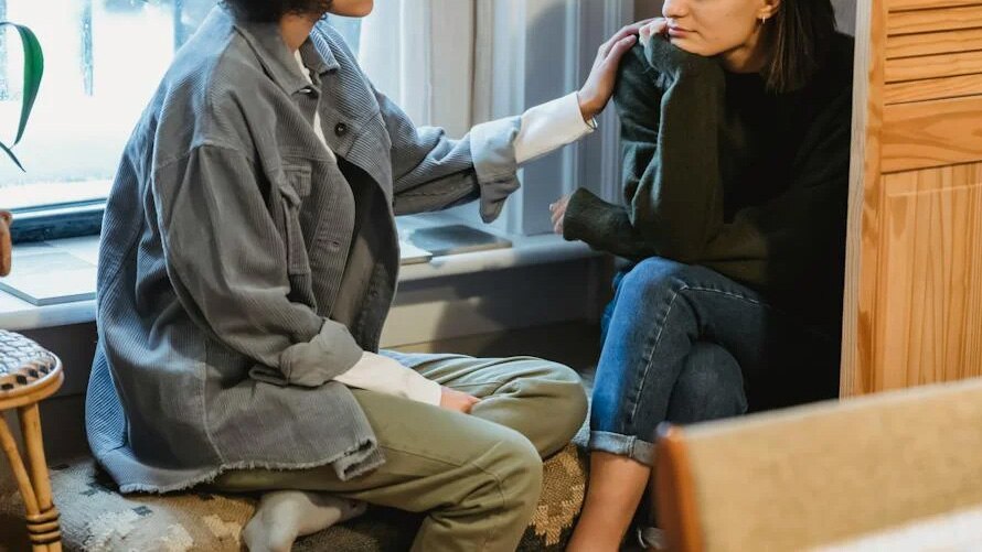 woman comforts friend with hand on shoulder in the home