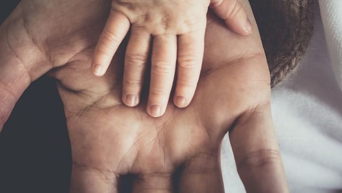 Picture child's hand resting on an adults hand