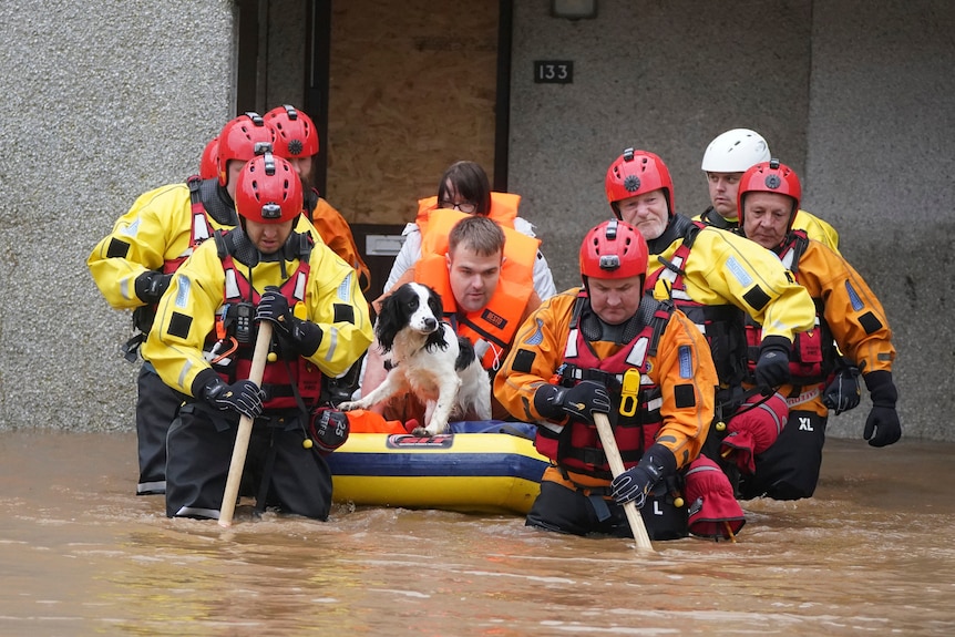 A man and dog are rescued from flood in inflatable dinghy by high-vis emergency workers