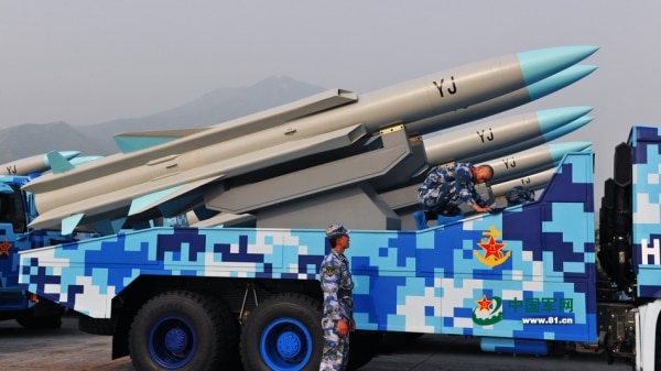 The missiles sit on a blue and white truck, they are grey with a blue tip, they have 'YJ' printed on them in black.