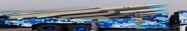 导弹坐在一辆蓝白相间的卡车上，它们是灰色带蓝色尖端，上面印有黑色的‘YJ’。” class=