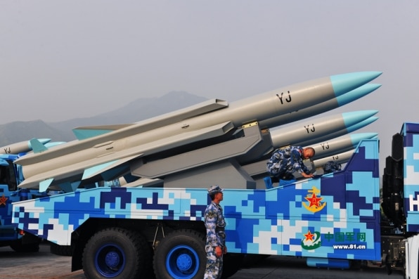 The missiles sit on a blue and white truck, they are grey with a blue tip, they have 'YJ' printed on them in black.