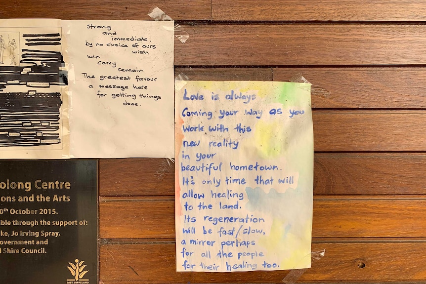 Handwritten notes stuck up on a wall. One is written in black pen, the other is written in watercolour