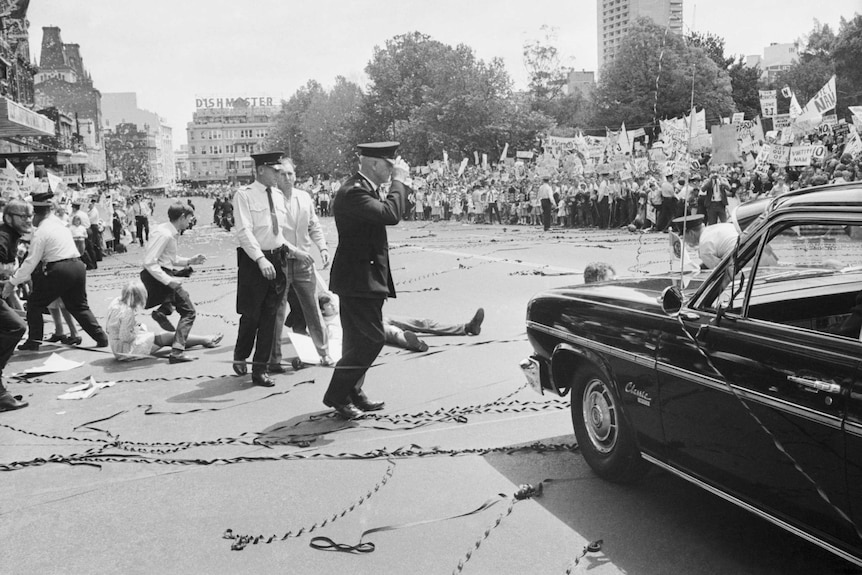 In front of a large crowd protesters jump in front of LBJ's car