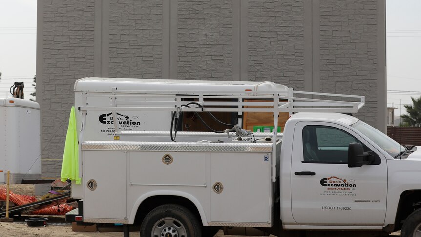 A grey concrete wall with a trailer parked in front of it.