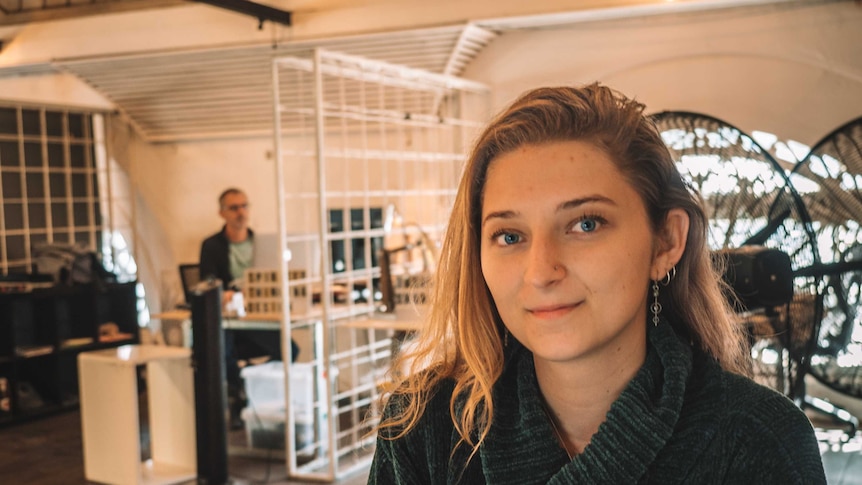 A young woman in a co-working office looks at the camera