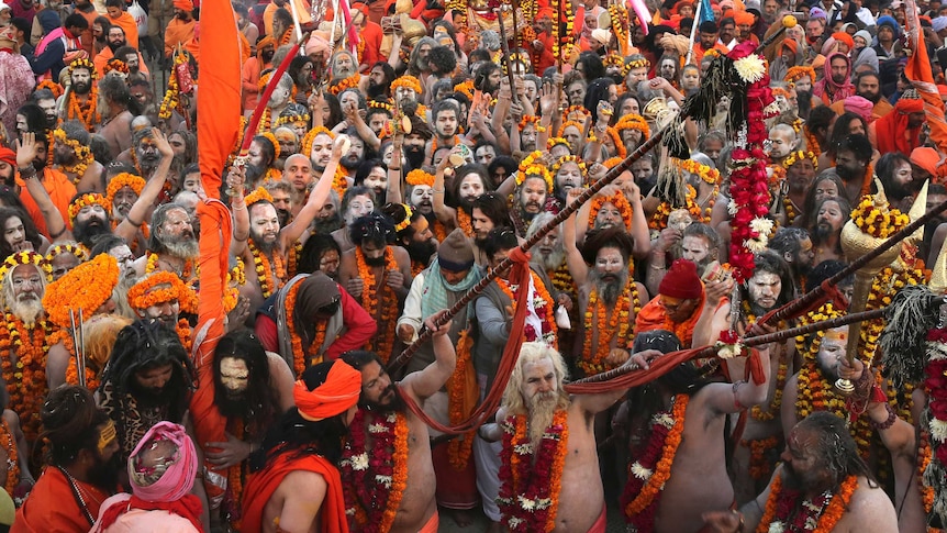 A huge crowd of Indian holy men wearing orange flowers and waving red and orange flags
