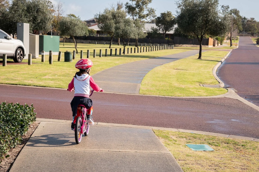 Young girl rides a bike on a pathway in a park.