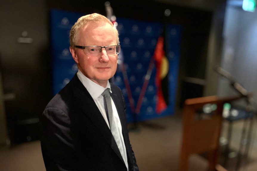 Philip Lowe looks at the camera, with a blurred podium in the background.