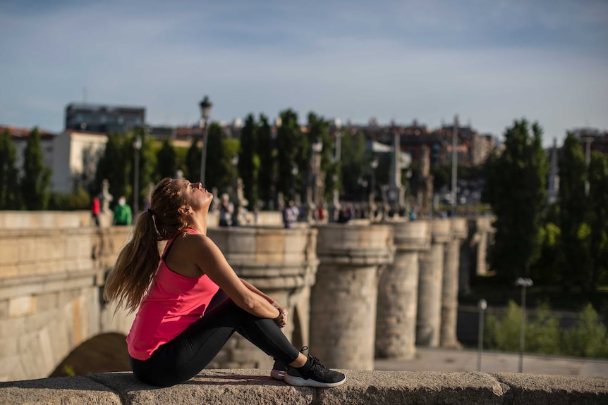 A woman enjoys the sun at the Toledo bridge in Madrid, Spain.