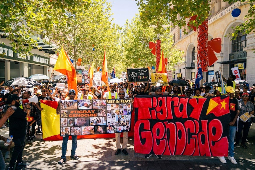 Hundreds of people march through Perth with colourful banners and flags.