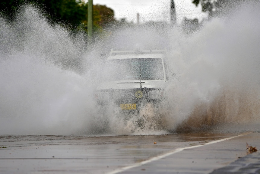 A white landcruiser driving through water and splashing water on both sides. 