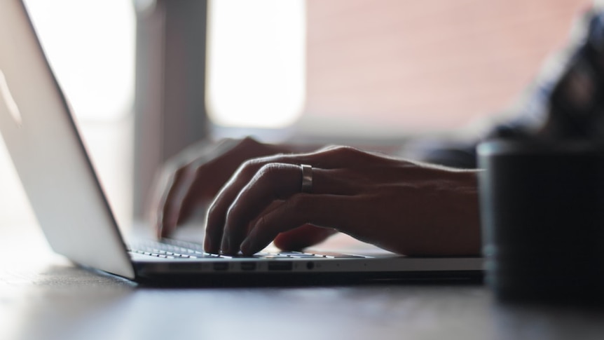 Hands are seen on the keyboard of a laptop.