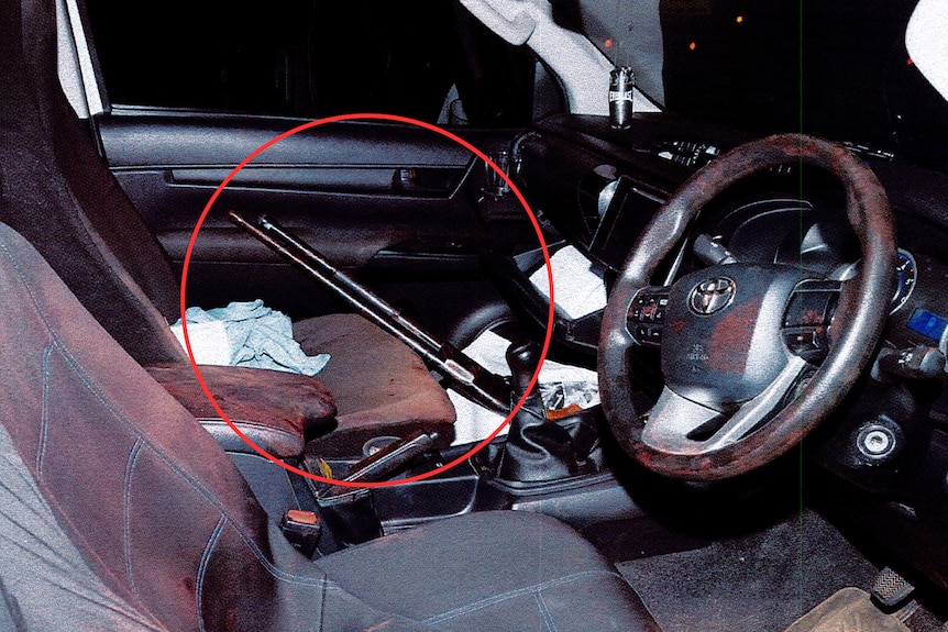 A gun resting against the passenger seat inside an empty car.