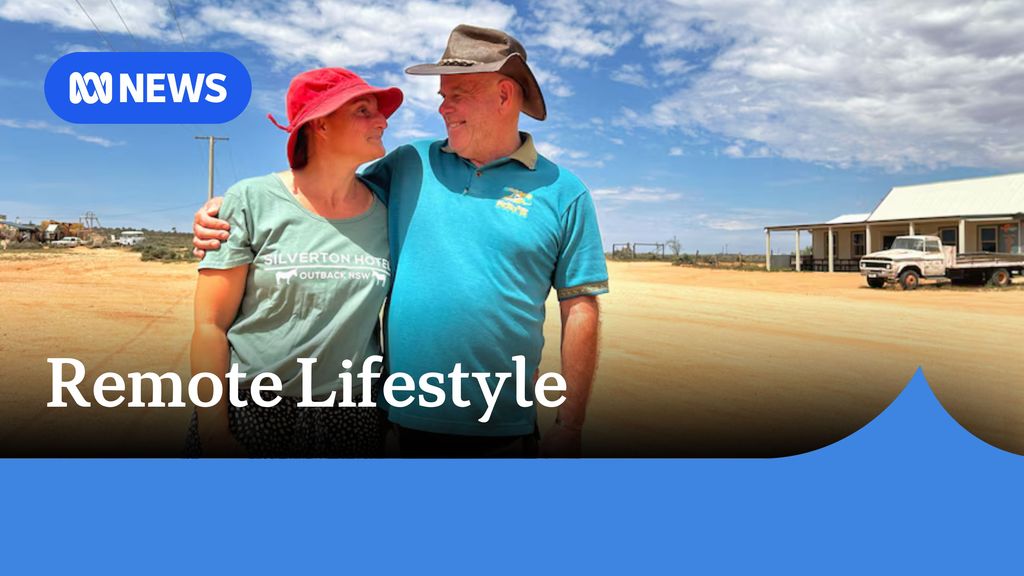 Remote Lifestyle: Man and woman embrace while wearing hats standing in dusty outback roadside. 