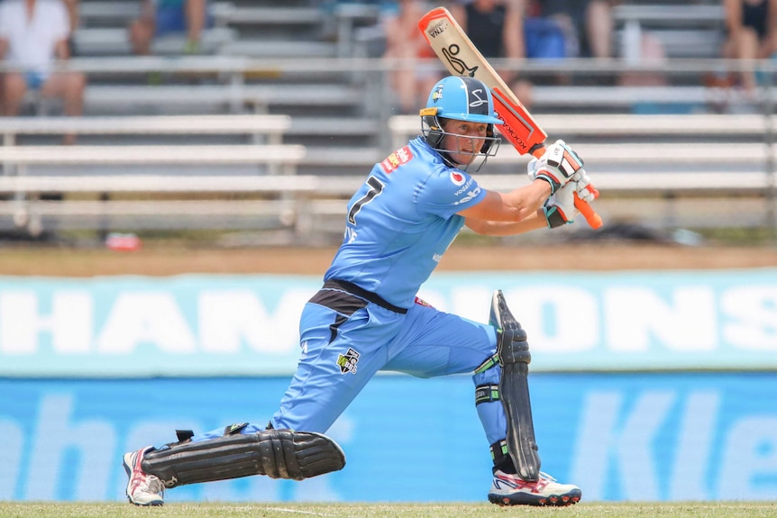 An Adelaide Strikers cricketer gets on one knee to hit a shot on the off-side in a WBBL semi-final.