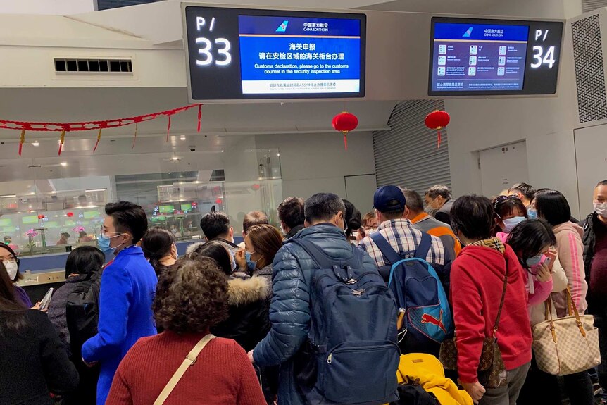 People crowded in front of information counters at Guangzhou Baiyun International Airport.