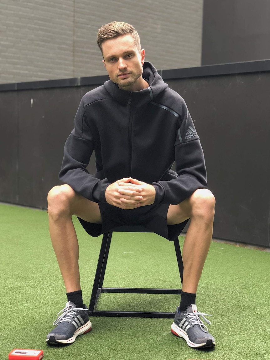 Joel Mason, wearing sports training attire, sits for a portrait.