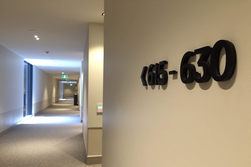 A hotel corridor with a sign pointing to rooms.