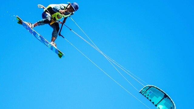 A kite surfers flies through the air.