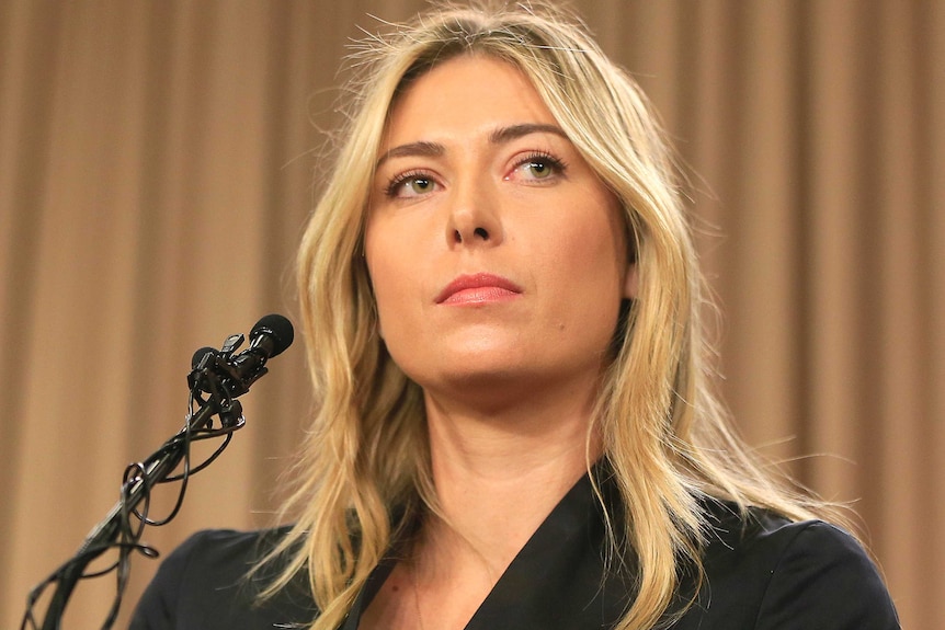 Maria Sharapova has a blank look on her face as she sits in front of a microphone.