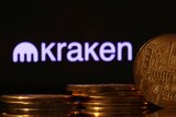 A number of golden, electronic-looking coins sit in front of an illuminated mauve logo which says "Kraken".