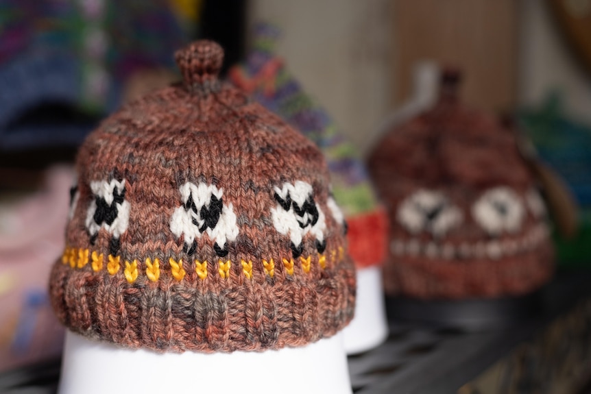 A brown beanie with white sheep knitted into the pattern
