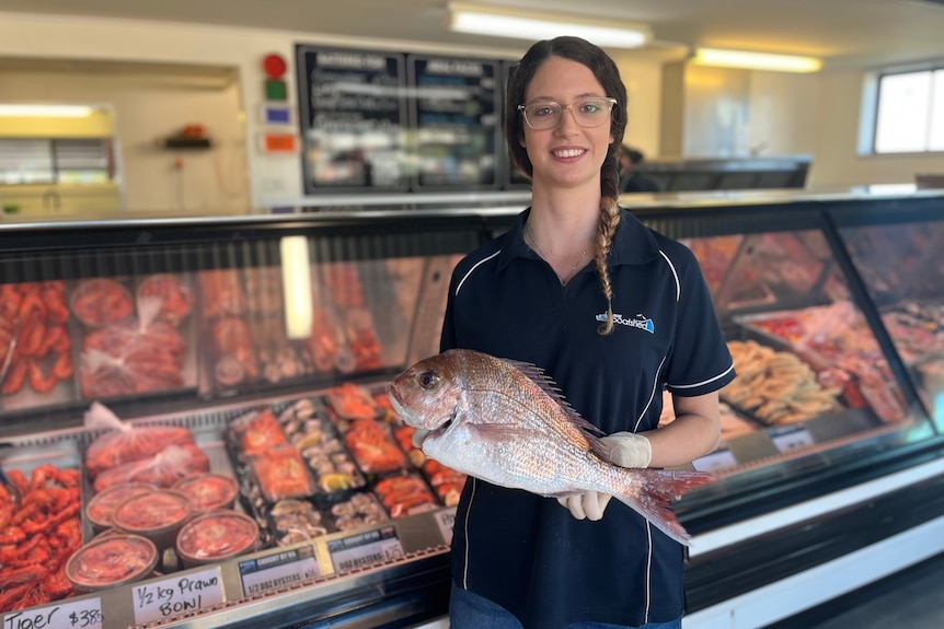 A woman stands with a fresh fish at the Innes Boat Shed in Baemans Bay. 