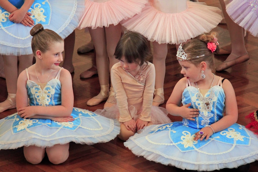 Young girls in ballet dress sitting on the floor