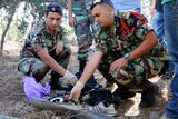 Army personnel inspect remains of rockets launched from Lebanon into Israel