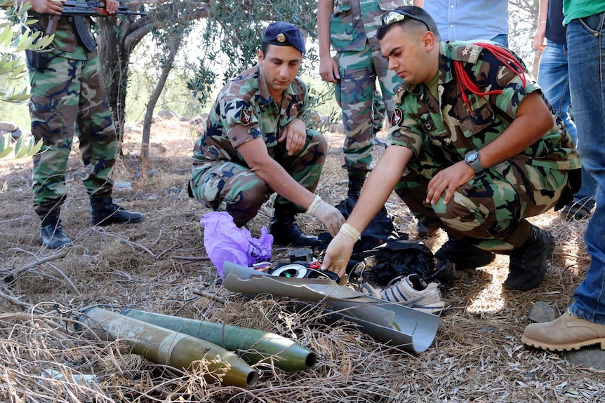 Army personnel inspect remains of rockets launched from Lebanon into Israel