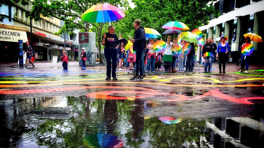 Colourful reflections in a paddle in Garema Place as people take part in the Spring Out Pride Parade.