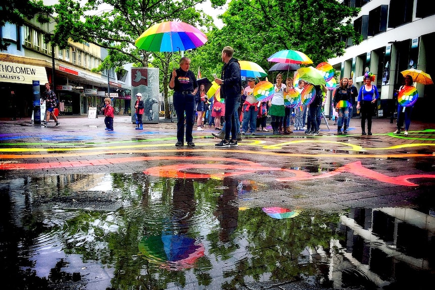 Colourful reflections in a paddle in Garema Place as people take part in the Spring Out Pride Parade.