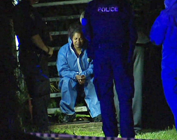 Liddel Ramsey, 24, sits in a hazmat suit in police custody at a home at Annerley.